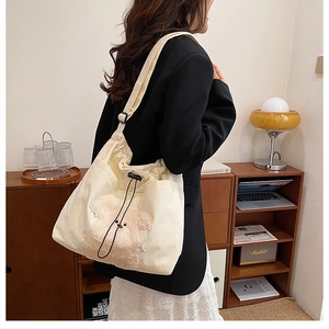 Detail of cream corduroy tote bag with plush bear decoration and adjustable drawstring strap