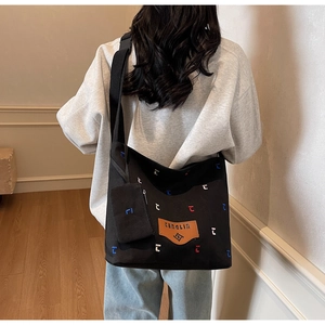 Detail of a large black canvas hobo bag with embroidery, adjustable strap and coin purse