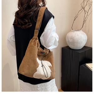 Detail of brown corduroy tote bag with plush rabbit decor and adjustable shoulder strap