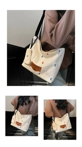 Detail of white canvas tote bag with contrast embroidery and mini coin purse accessory