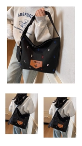 Detail of black canvas bucket bag with letter embroidery and matching mini pouch
