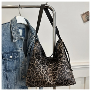 Dettaglio della borsa tote leopardata con fiocco nero appesa a un appendino in metallo