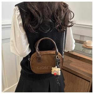 Detail of brown suede mini bowling bag with embossed logo and cute plush charm pendant