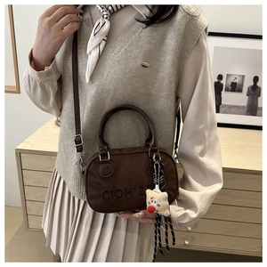Detail view of deep brown suede texture bag with embossed logo and cartoon charm