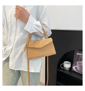 Detail of hand-woven straw shoulder bag with envelope flap and decorative knotted rope strap