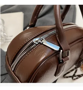 Gros plan sur la fermeture éclair argentée et le cuir marron texturé du sac vintage