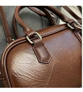 Détail macro du cuir plissé marron foncé avec anneaux métalliques et coutures fines