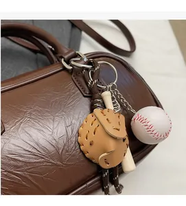 Détail d'un porte-clé mini gant et batte de baseball sur un sac en cuir texturé