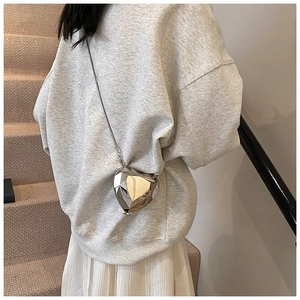 Pochette coeur en acrylique argenté avec facettes géométriques portée en bandoulière