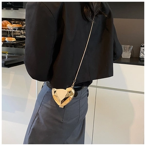 Détail du sac à bandoulière doré en forme de cœur avec facettes et chaîne en métal