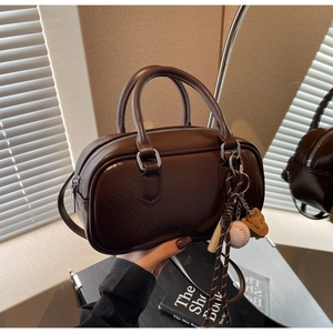 Détail du sac Boston marron café avec texture cuir et pendentif de baseball décoratif