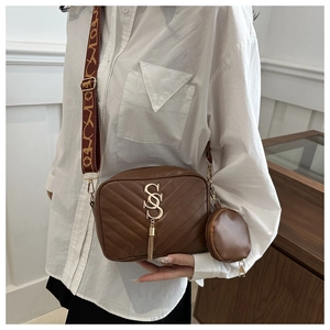 Detail of brown quilted crossbody bag with gold SS logo and matching round coin purse
