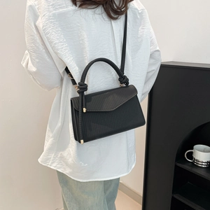 Minimalist black woven texture crossbody bag with unique knot handle shown on a model
