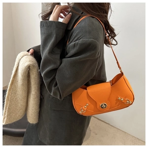 Detail view of stylish orange faux leather underarm bag with gold lock and rivets