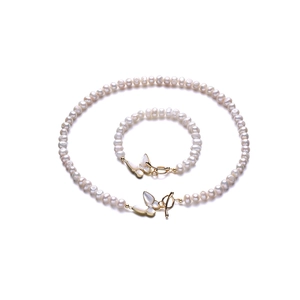 Détail de parure en perles d'eau douce avec fermoir papillon en nacre et éléments dorés
