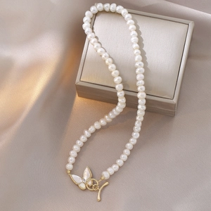 Détail du collier de perles d'eau douce avec fermoir papillon doré sur soie