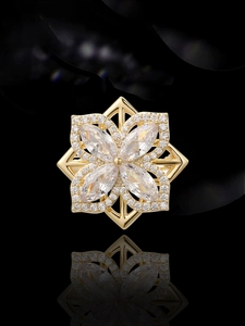 Makro-Detail der goldenen Blütenbrosche mit Steinen im Marquise-Schliff und Diamanten