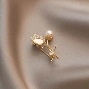 Elegant gold tulip brooch with white pearl and sparkling crystals on silk background