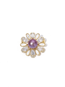 Détail d'une broche fleur avec perle violette et pétales en zircon sur base dorée