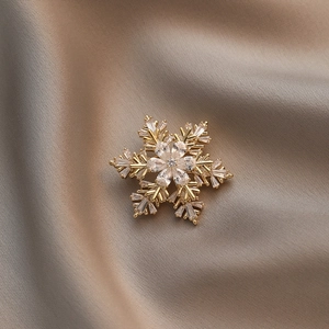 Broche flocon de neige dorée avec zircons incrustés sur élégant satin de champagne