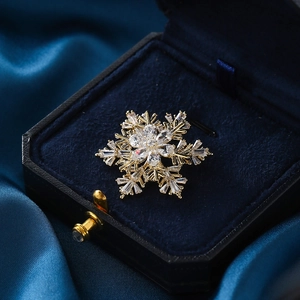 Élégante broche flocon de neige en or avec zircons étincelants sur velours et soie bleus