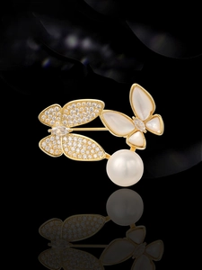 Detailed close-up of double butterfly brooch with zircon, mother of pearl and a large pearl