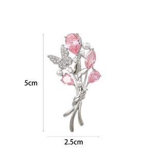 Broche bouquet argentée élégante avec pierres roses, perles et détail de papillon