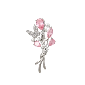 Détail macro d'une broche argentée avec pierres roses, perles et papillon diamanté étincelant
