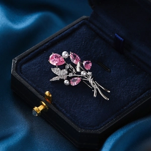 Élégante broche bouquet avec pierres roses, perles et détails de papillon en cristal