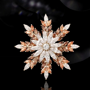 Exquisite snowflake brooch with amber and white marquise crystals on a black reflective surface