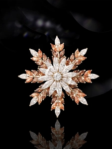 Detailed view of a gold snowflake brooch with amber and clear marquise gemstones