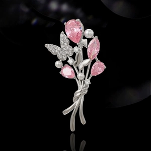 Broche bouquet à cristaux roses, perles et papillons sur fond noir avec reflets