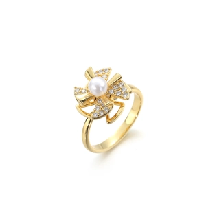 Drehbarer Windradring in Gold mit weißer Perle und funkelnden Blütenblättern aus Zirkonia