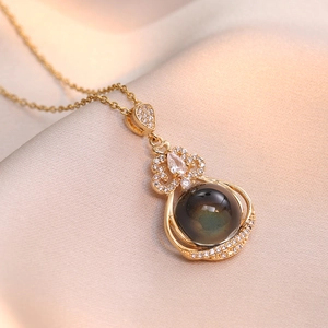 Elegant gold gourd necklace with iridescent gemstone and crystals on champagne silk