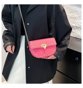 Détail d'un sac bandoulière rose en cuir grainé avec rivets dorés et fermoir rotatif