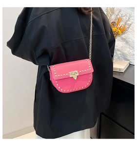 Detail of pink crossbody bag with gold studs and chain strap shown on a model