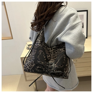 Detail of leopard print hobo bag with black butterfly leather patch and lace-up design