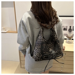 Détail du sac léopard français avec écusson papillon noir et nœud décoratif en ruban