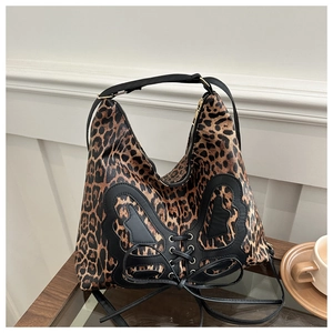 Detail of leopard print tote bag featuring a large black leather bow and cross-tie design