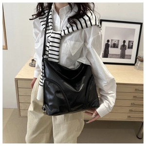 Detail of black leather hobo bag featuring functional front diagonal zippers