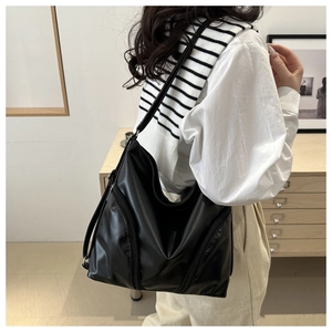 Detailed view of black soft leather tote bag with functional zippers on a female model