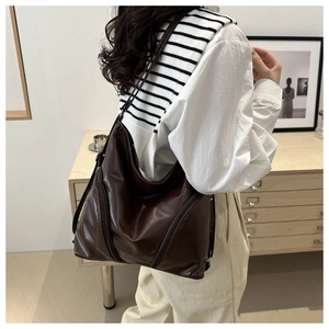 Detail view of large dark brown soft leather hobo bag with side zippers for commuting