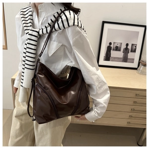 Macro shot of dark brown soft leather tote bag showing stylish dual diagonal zippers