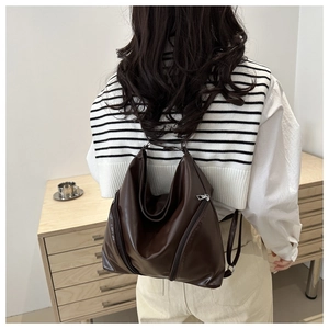 Detail of soft dark brown leather backpack with modern geometric fold and side zipper