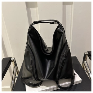 Detail of black leather backpack featuring symmetrical diagonal zippers and large top handle