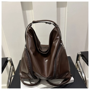 Detail view of large dark brown soft leather tote bag with decorative vertical zippers