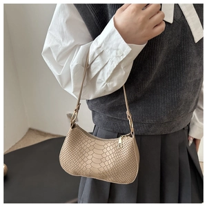 Detail of light beige faux snakeskin texture on a shoulder bag with gold metal rings