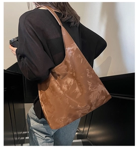 Dettaglio di una borsa hobo vintage marrone con pelle lucida e tracolla larga morbida
