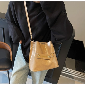 Detail of a brown leather bucket bag with a golden chain and Fashion logo plaque