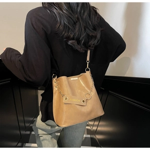Close-up of brown leather bucket bag with metal chain strap and fashion tag detail